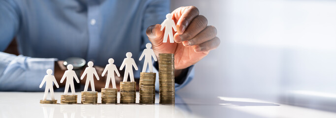 Human Hand Placing Human Figure On Increasing Stacked Coins