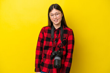 Young photographer Chinese woman isolated on yellow background with glasses and happy