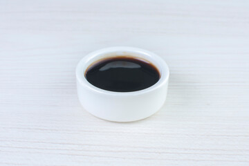teriyaki sauce, in white ceramic bowl on white wooden background