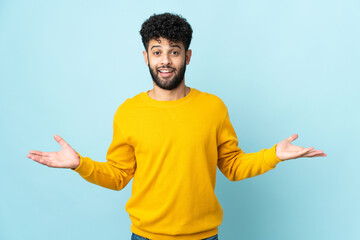 Young Moroccan man isolated on blue background with shocked facial expression