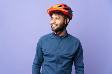 Young Moroccan cyclist man isolated on purple background looking side - obrazy, fototapety, plakaty