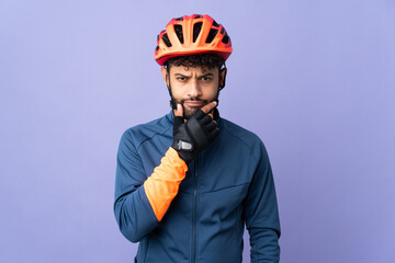 Young Moroccan cyclist man isolated on purple background thinking - obrazy, fototapety, plakaty