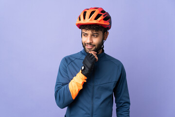 Young Moroccan cyclist man isolated on purple background looking to the side and smiling - obrazy, fototapety, plakaty