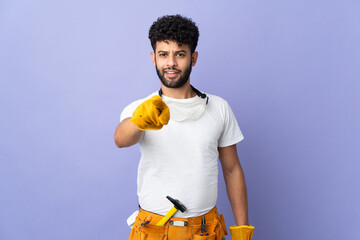 Young electrician Moroccan man isolated on purple background surprised and pointing front
