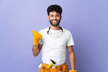 Young electrician Moroccan man isolated on purple background pointing to the side to present a product - obrazy, fototapety, plakaty