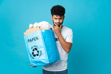 Young Moroccan man holding a recycling bag full of paper to recycle over isolated background...