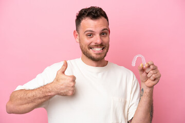 Brazilian man holding invisible braces with thumbs up because something good has happened