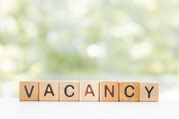 vacancy word is made of wooden blocks lying on the table, concept, green background