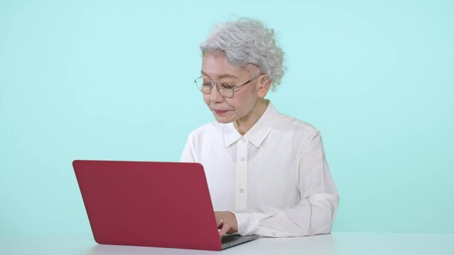 ノートパソコンを使うシニア女性
