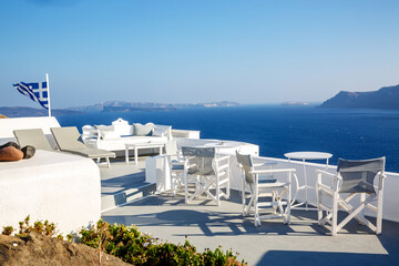 A sun terrace for rest with a white wooden table and chairs in Thira, Santorini island, Greece