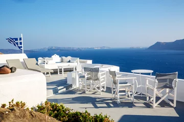 Poster A sun terrace for rest with a white wooden table and chairs in Thira, Santorini island, Greece © 9parusnikov
