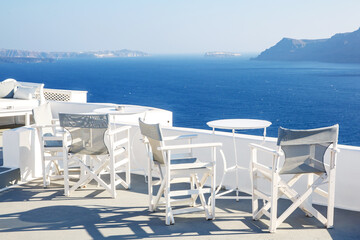 A sun terrace for rest with a white wooden table and chairs in Thira, Santorini island, Greece