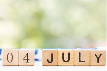 Date of 4 july on wooden cubes with american flag on wooden background. USA independence day. Space for text.