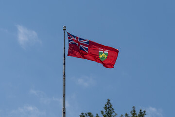 
Flag of Ontario waving in the wind with blue sky in the background.  The flag of Ontario is the provincial flag of Ontario, Canada.
