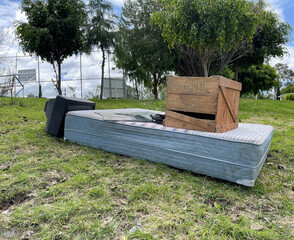 Abandoned mattress, tv and wooden box in park