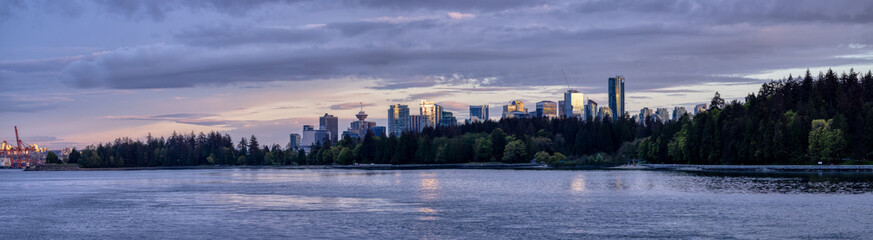 Fototapeta na wymiar Seawall around Stanley Park with Highrise Buildings in background. Modern City Skyline. Downtown Vancouver, British Columbia, Canada. Colorful Sunset Sky