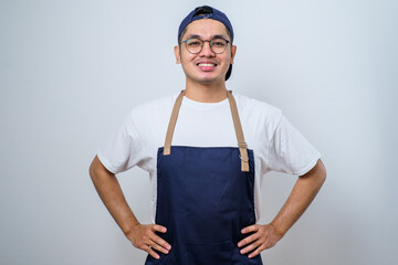 Young asian barista man wearing apron standing with hands on his waist
