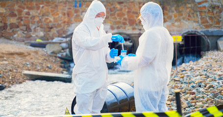 Team of Scientists in protective suits or Biologist collect sample of dirty water smelly and toxic water from factory  took a sample of waste water for analysis. Pollution and environment problems