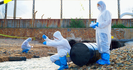 Team of Scientists in protective suits or Biologist collect sample of dirty water smelly and toxic water from factory  took a sample of waste water for analysis. Pollution and environment problems