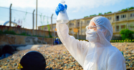 Asian women scientists in protective suits or Biologist collect sample of dirty water smelly and...