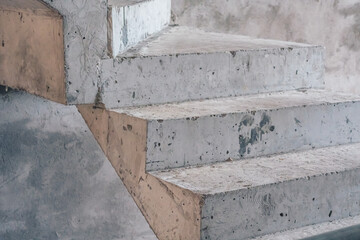 Bare grey cement concrete stairs leading up, construction site, unfinished staircase architecture, copy space close-up, abstract background, city inside building, geometry, visible texture, industrial