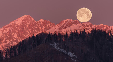 Full moon setting behind the mountains