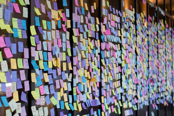 Colorful sticky notes with a variety of messages and emojis are seen on a storefront window at a...