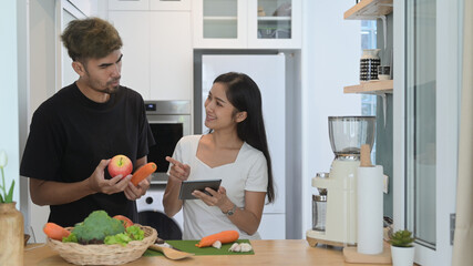 Happy young couple preparing ingredient for making making green detox smoothie in home kitchen
