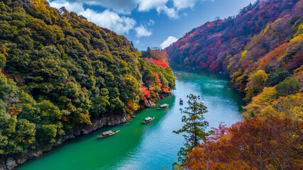 Arashiyama in autumn season along the river in Kyoto, Japan, Aerial view Arashiyama Togetsu or Togetsukyo bridge ancient architecture and boats in Katsura river, Arashiyama, Kyoto, Japan, Asia.