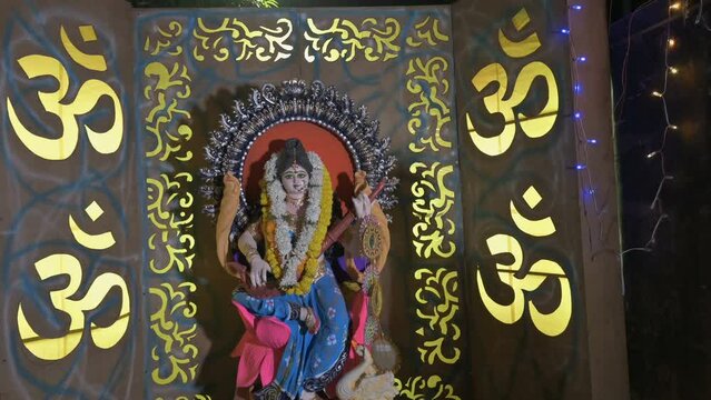 Idol of Goddess Saraswati being worshipped inside pandal, Howrah, West Bengal, India. Sanskrit Om letter is written in Bengali language.