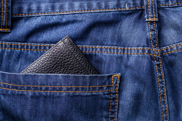 Black men's wallet in the back pocket of old shabby jeans