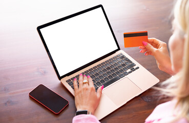 Closeup photo of person using laptop computer and holding credit card in hand