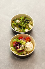 Vegetarian healthy bowls with bulgur, broccoli, greens, feta cheese and poached egg isolated on gray background. Healthy food delivery service and daily ration concept.