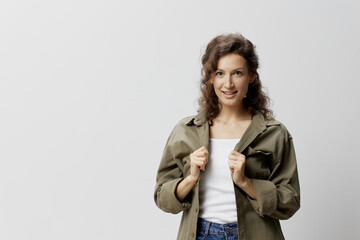 Happy cheerful concentrated curly beautiful woman in casual khaki green shirt holds collar looks at camera posing isolated on over white background. People Emotions Lifestyle concept. Copy space