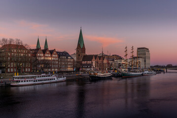 View of Bremen with the buildings, bridges and ships reflecting in the river at sunset - obrazy, fototapety, plakaty
