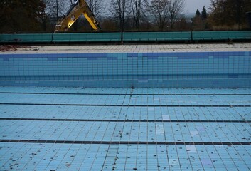 Schwimmbad Panorama mit blauem Schwimmbecken, beigen Beckenrandkacheln, blauer Betonbank,...