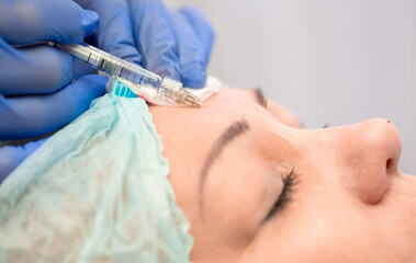 Injection facial rejuvenation. The cosmetologist injects cosmetic injections into the muscles of...