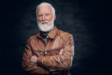 Portrait of grandfather with stylish hairstyle dressed in leather jacket against dark background.