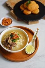 a bowl of beef vegetables clear soup served with rice named soto in Bahasa