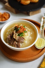 a bowl of beef vegetables clear soup served with rice named soto in Bahasa