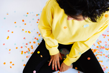 woman surrounded by coloured confetti with a yellow shirt