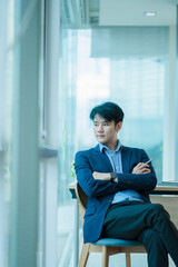 Young Asian businessman sits in a chair with pen in his spare time to relax in his office.