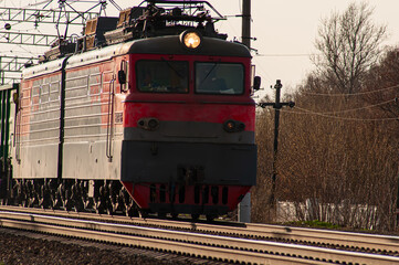 A powerful red diesel locomotive pulls a long freight train along the tracks