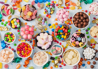 Milk chocolate and jelly gums candies on blue background with liquorice allsorts and strawberry...