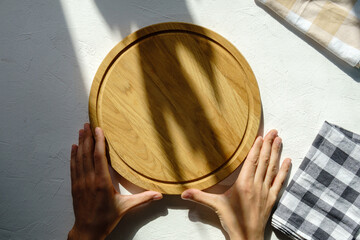 Empty wooden plate with a napkin on a white stone table, top view. Wooden cutting board on a concrete background. Copy space