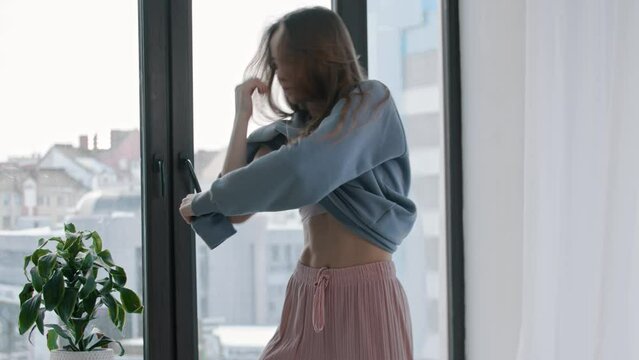 Young woman dancing and taking off her sweater