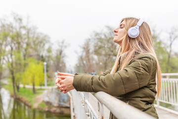 Relaxed woman wearing headphones breathing fresh air listening to music in a park