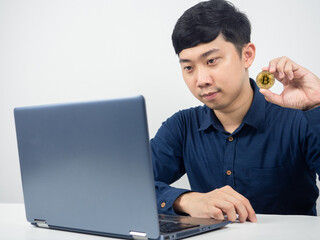 Man sit and looking at laptop show bitcoin in hand