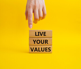 Live your values symbol. Concept words 'Live your values' on wooden blocks. Beautiful yellow background. Businessman hand. Business and Live your values concept. Copy space.