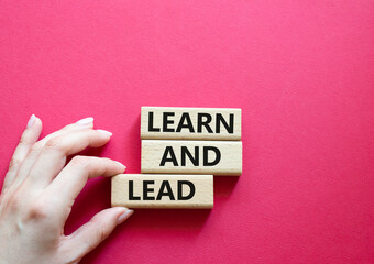Learn and lead symbol. Concept words 'Learn and lead' on wooden blocks. Beautiful red background....